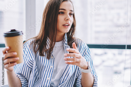 Young employee with takeaway beverage talking during break