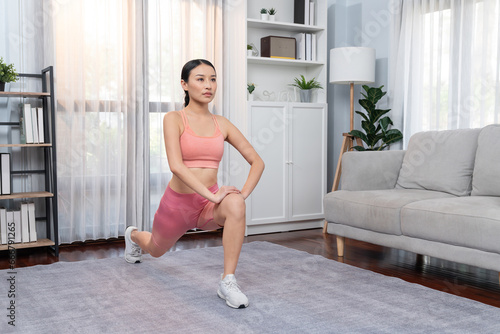 Young attractive asian woman in sportswear stretching before fitness exercise routine. Home body workout with healthy athletic woman warming up. Vigorous
