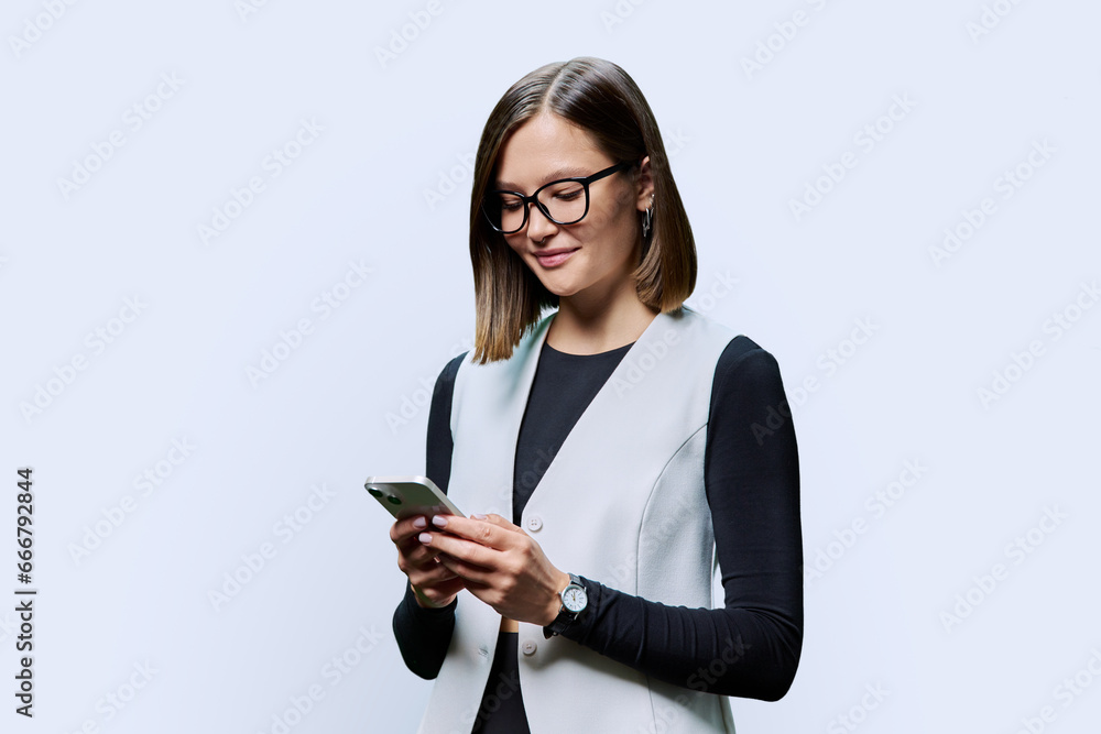 Young confident woman with smartphone in hands on white studio background Young confident woman with smartphone in hands on white studio background