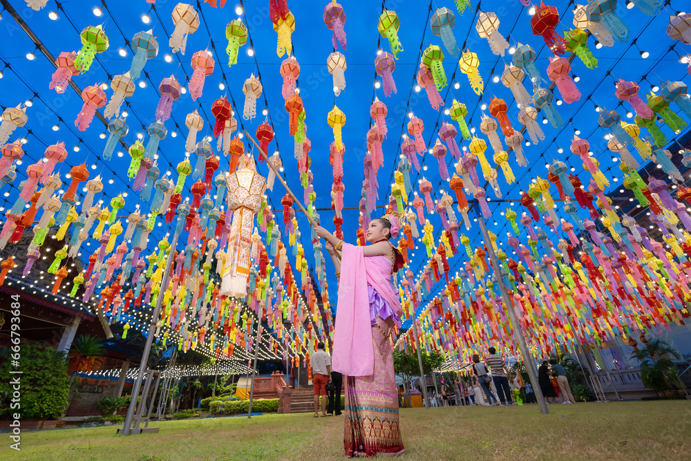 Lantern Festival or Yi Peng Festival in Hundred Thousand Lantern with the pretty Asian girl wearing beautiful Thai traditional dress Lanna style Phra That Hariphunchai temple Lamphun, Thailand. - obrazy, fototapety, plakaty 