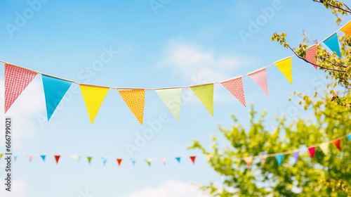 string of colorful pennant against blue sky in the garden as a summer party decoration © bmf-foto.de
