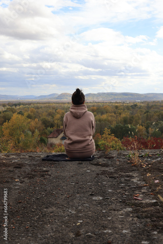 woman sitting on the top of a rock and looking to the side.