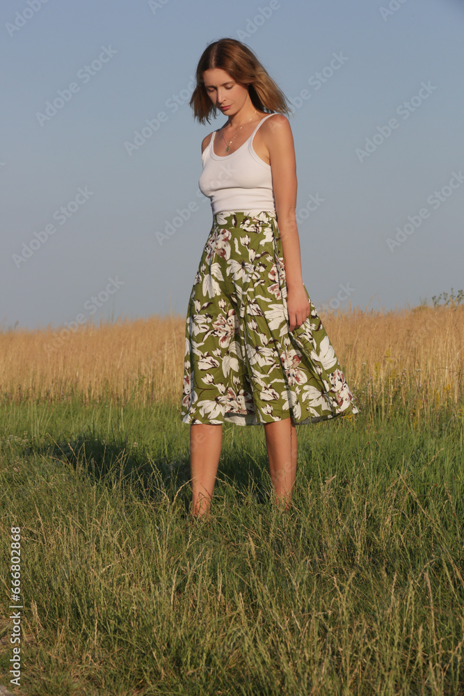 Candid outdoor portrait on the meadow of young woman linen skirt and white top. Casual summer fashion. Candid outdoor portrait on the meadow of young woman linen skirt and white top. Casual summer fashion.