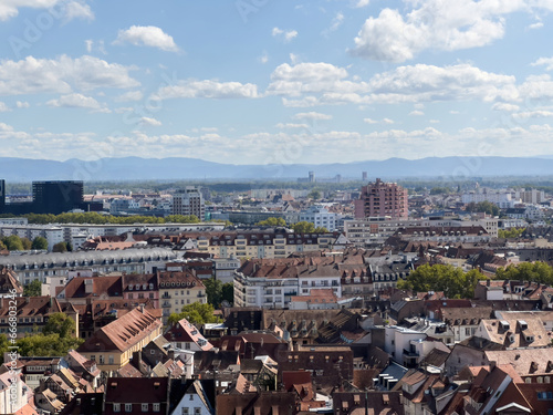 Strasbourg Center: Timbered Alsatian houses and tall buildings frame the view of the Vosges Mountains in the distance - aerial view