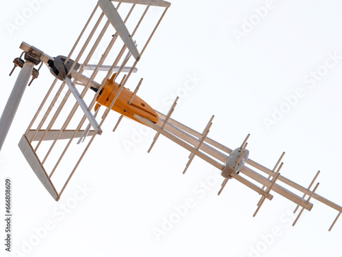 Captured from a low-angle perspective, an antenna featuring steel components and a distinct yellow plastic section excels in receiving both analog and digital signals in the realm of