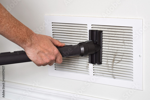 фотографія Person's hand vacuuming dirty return air vents