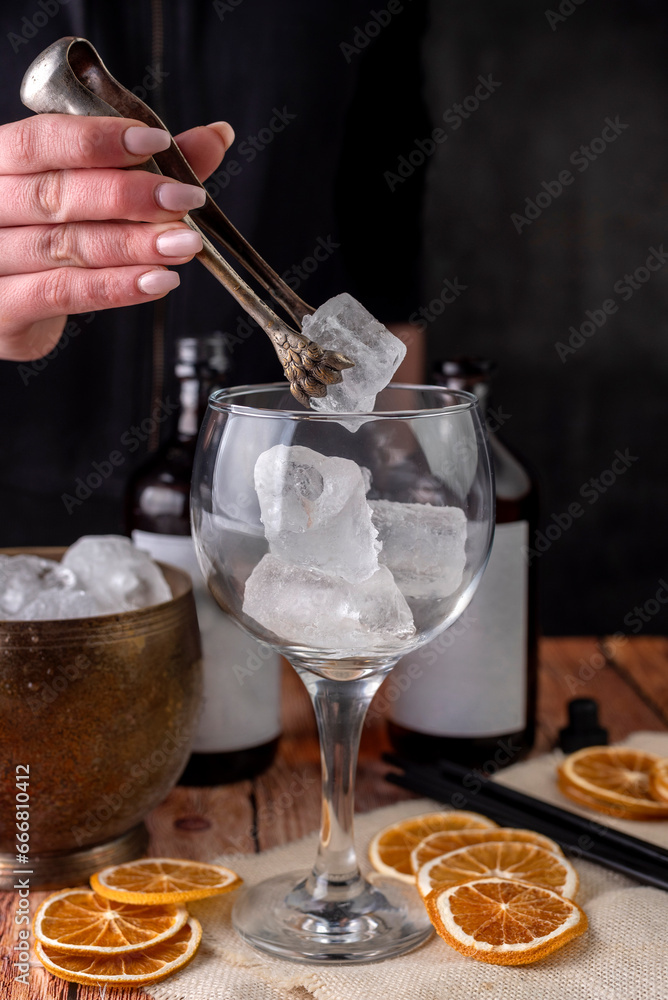 preparation of a shot of artisanal gin with lemon and orange slices and ice with the hand of a bartender