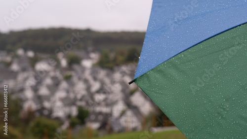 Woman stands in the rain with an umbrella and enjoys the view of an old town with half-timbered houses. Selective focus