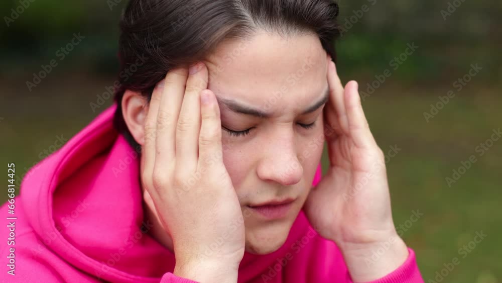 Young adult sports man suffering from headache while standing in an urban park Young adult sports man suffering from headache while standing in an urban park