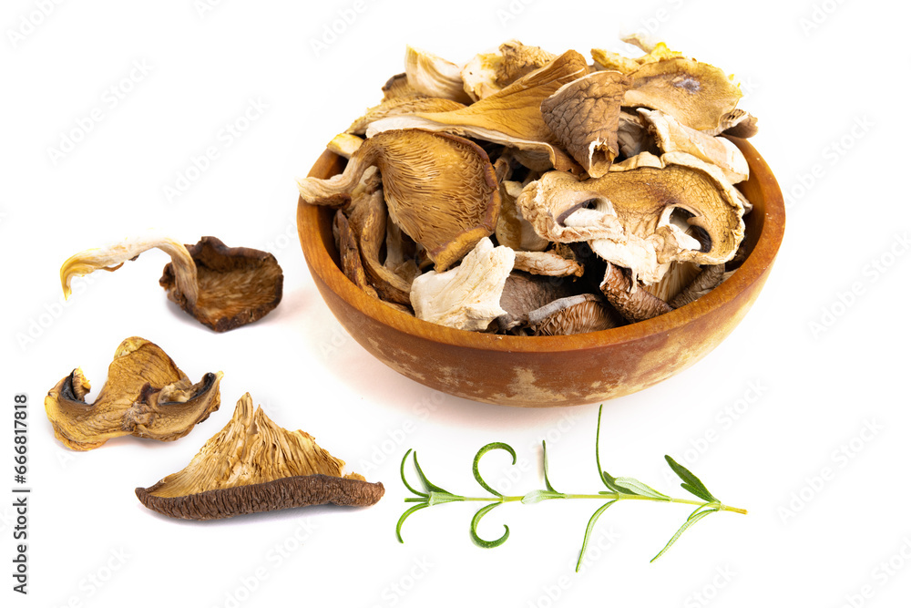 Assorted edible dried mushrooms in a wooden bowl isolated on a white background. Assorted edible dried mushrooms in a wooden bowl isolated on a white background.