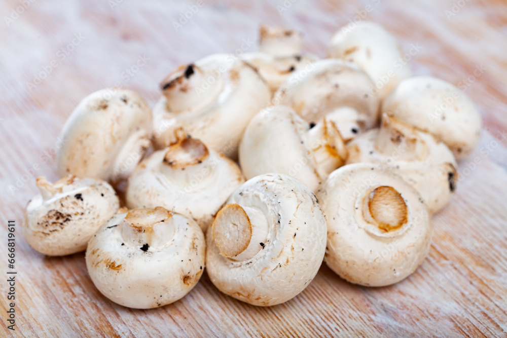 Image of raw white champignons on wooden surface in kitchen