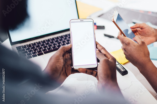 Black coworkers surfing Internet on smartphones at workplace