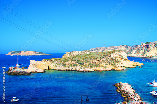 Fototapeta Naklejka Na Ścianę i Meble -  Peculiar view from Tremiti Islands (Isole Tremiti) at different rocky spurs, in the middle and on the edges, surrounded by the blue and azure Adriatic Sea, crossed by motorboats, under a gradient sky