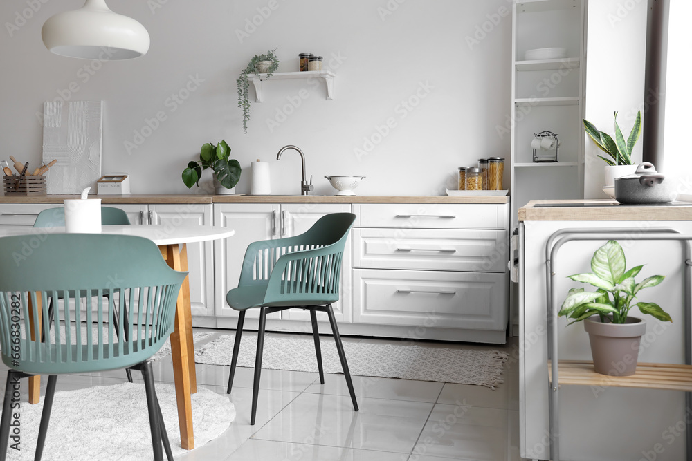 Interior of light kitchen with dining table and white counters Interior of light kitchen with dining table and white counters