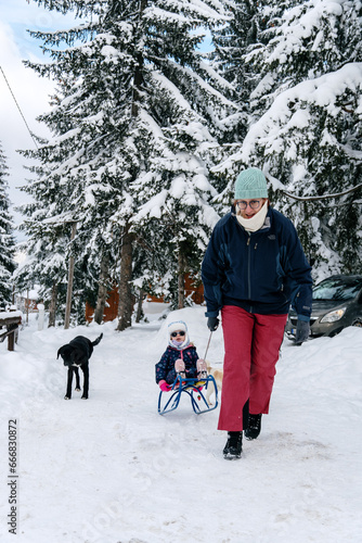 Little girl playing with mother on deep snow