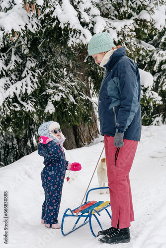 Little girl playing with mother on deep snow