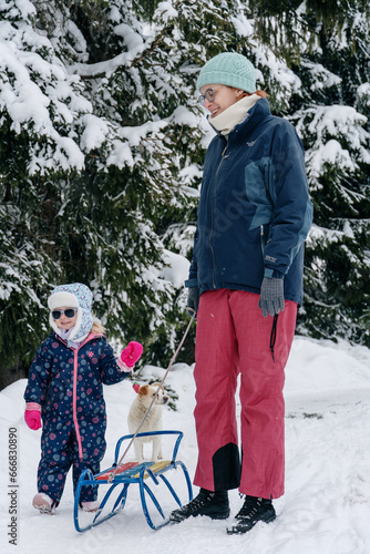 Little girl playing with mother on deep snow