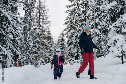 Little girl playing with mother on deep snow