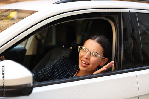 Stressed driver screaming in her car. Stuck in traffic jam