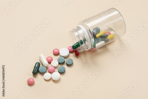 Jar with different scattered pills on beige background