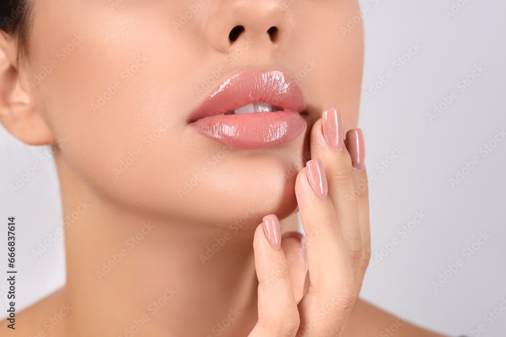 Young woman with beautiful lips on light background, closeup