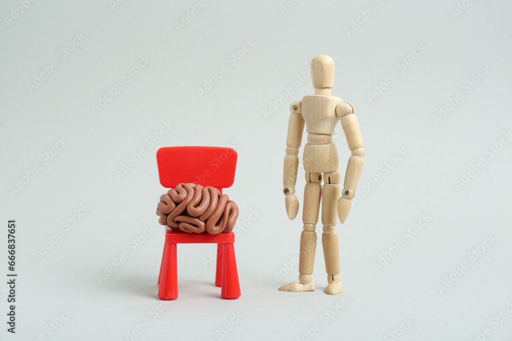 Mini chair with brain made of plasticine and wooden human model on white background Mini chair with brain made of plasticine and wooden human model on white background