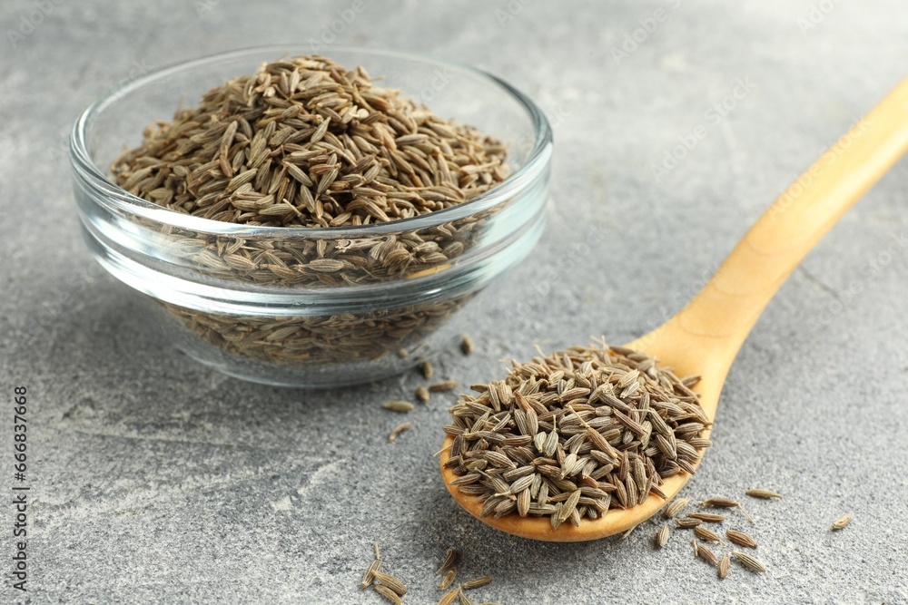 Bowl of caraway seeds and spoon on grey table, closeup Bowl of caraway seeds and spoon on grey table, closeup