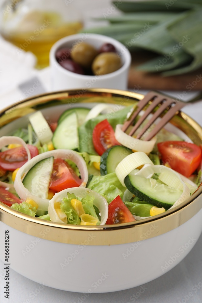 Bowl of tasty salad with leek, tomatoes and cucumbers on white table, closeup Bowl of tasty salad with leek, tomatoes and cucumbers on white table, closeup