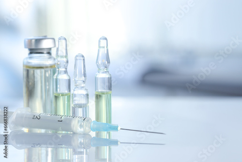 Glass vial, ampoules and syringe on white table, closeup. Space for text