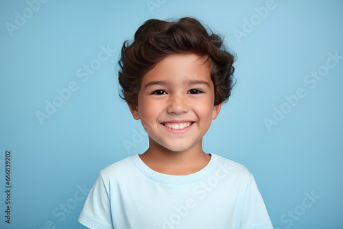 Portrait of a happy young fictional child smiling. Little boy wearing a blank blue t-shirt. Isolated on a plain colored background. Generative AI.