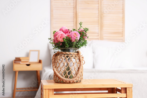 Wicker vase of beautiful pink dahlias on coffee table in bedroom