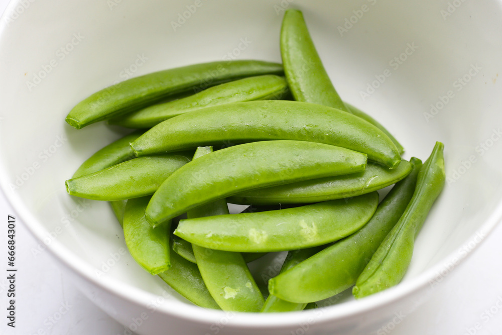 Fresh young green peas in white bowl