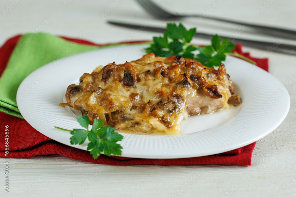 homemade baked chicken fillet steak with mushrooms and cheese on plate on red and green napkin on white wooden table. Party christmas menu homemade baked chicken fillet steak with mushrooms and cheese on plate on red and green napkin on white wooden table. Party christmas menu
