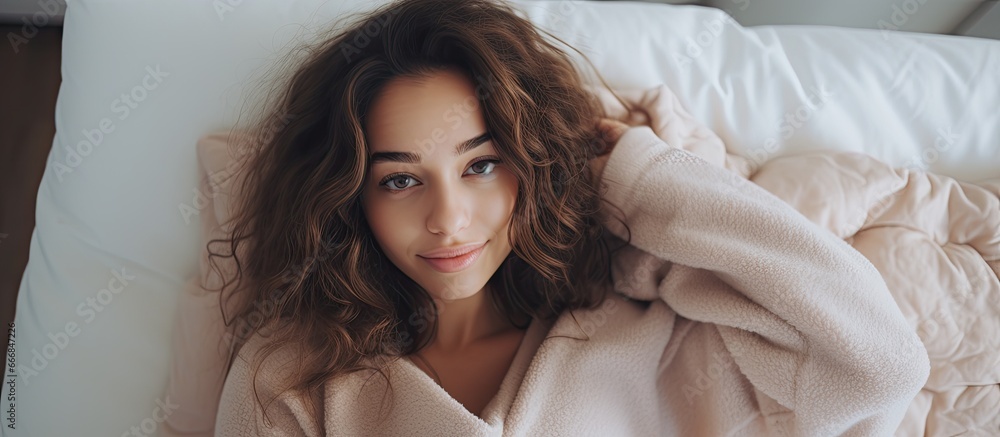 Naklejka premium Stunning girl in cozy sweater on bed at home