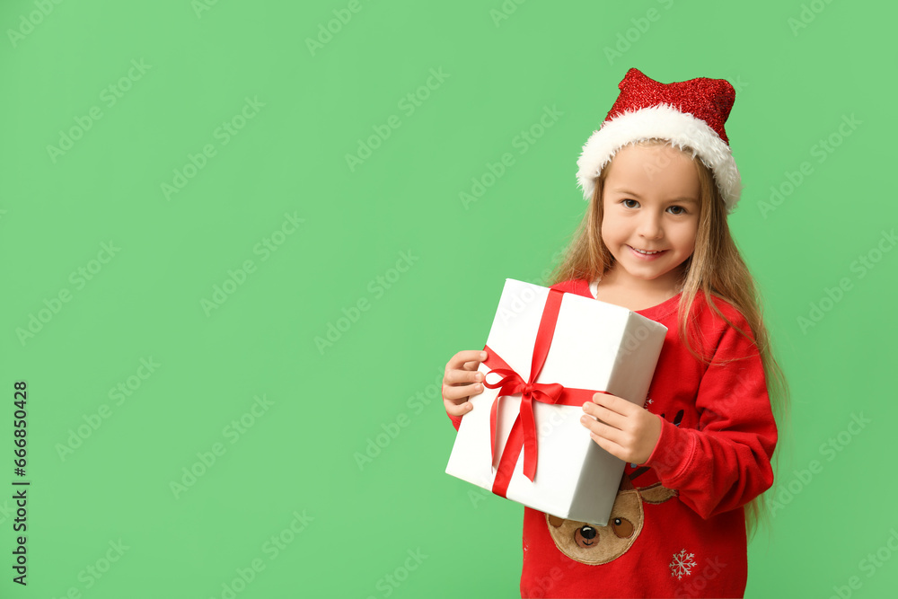Cute little girl in elf costume with gift box on green background Cute little girl in elf costume with gift box on green background