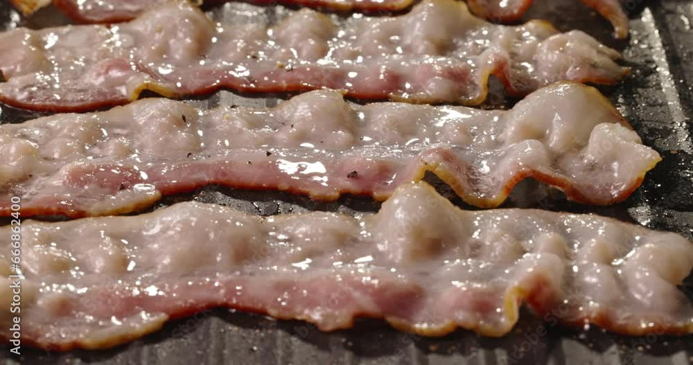 Frying halal beef bacon in pan side view close up. Smoked bacon rasher