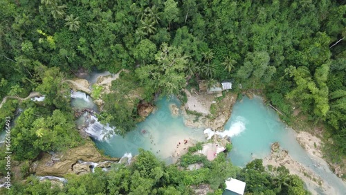 Multi-tier Kawasan falls with people canyoneering in waterfall Blue pools amid lush tropical jungle. Aerial