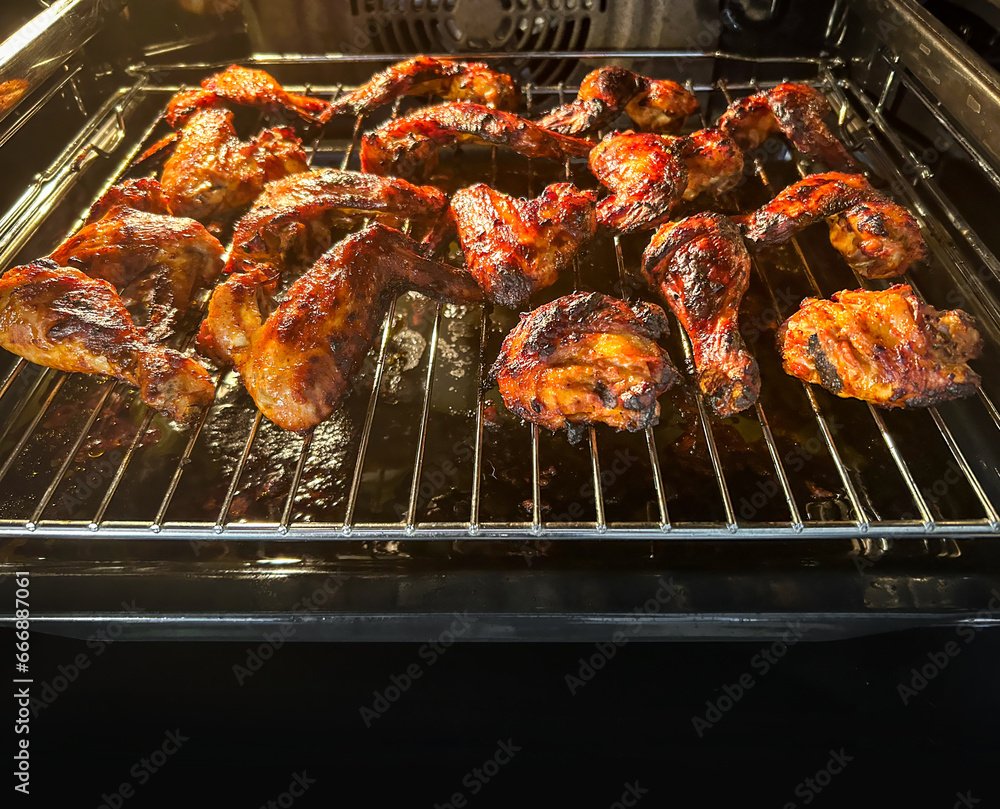 Grilling marinated chicken wings on grill in oven