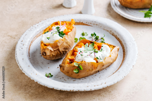 Whole baked sweet potatoes with spices, herbs and sour cream. Selective focus.