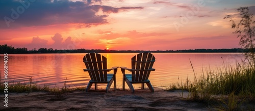 Fototapeta Naklejka Na Ścianę i Meble -  Chairs made of wood by peaceful lake during sunset