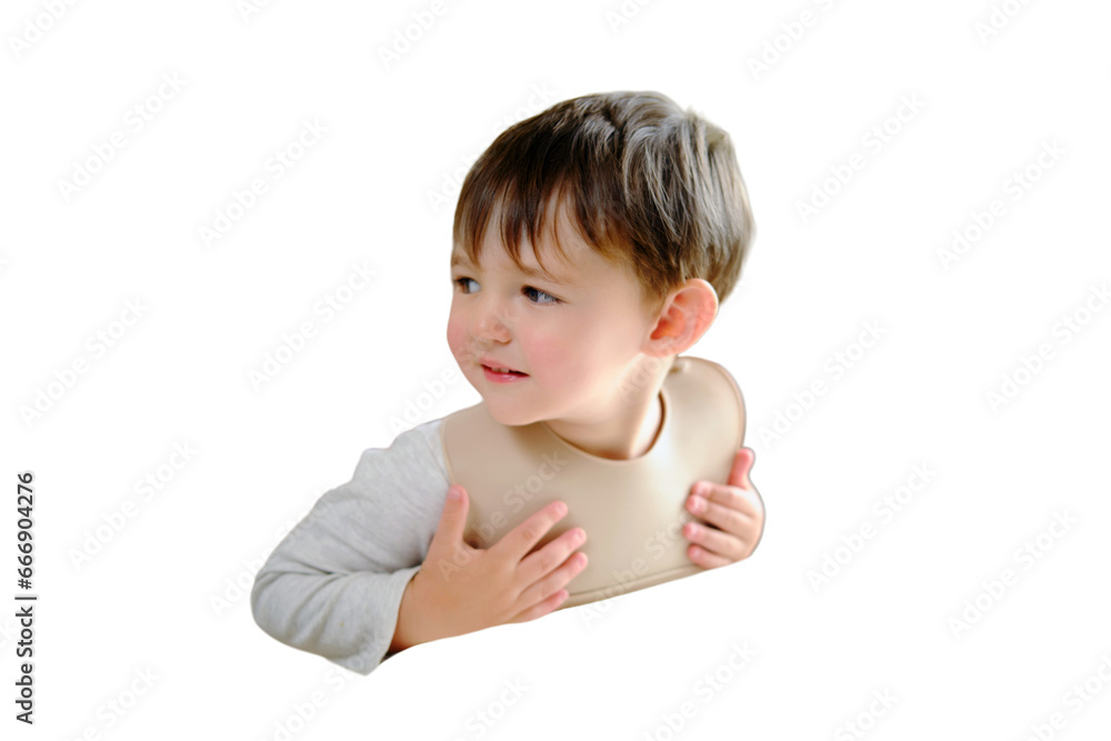 The child is impatiently waiting for food sitting at the table in a bib, isolated on white background. Kid boy aged two years (two-year-old) The child is impatiently waiting for food sitting at the table in a bib, isolated on white background. Kid boy aged two years (two-year-old)