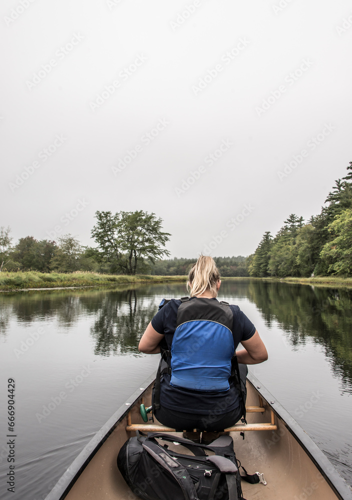 blonde Girl Canoe ride exploring nature on morning mist Kejimkujik National Park Wilderness Nova Scotia Canada