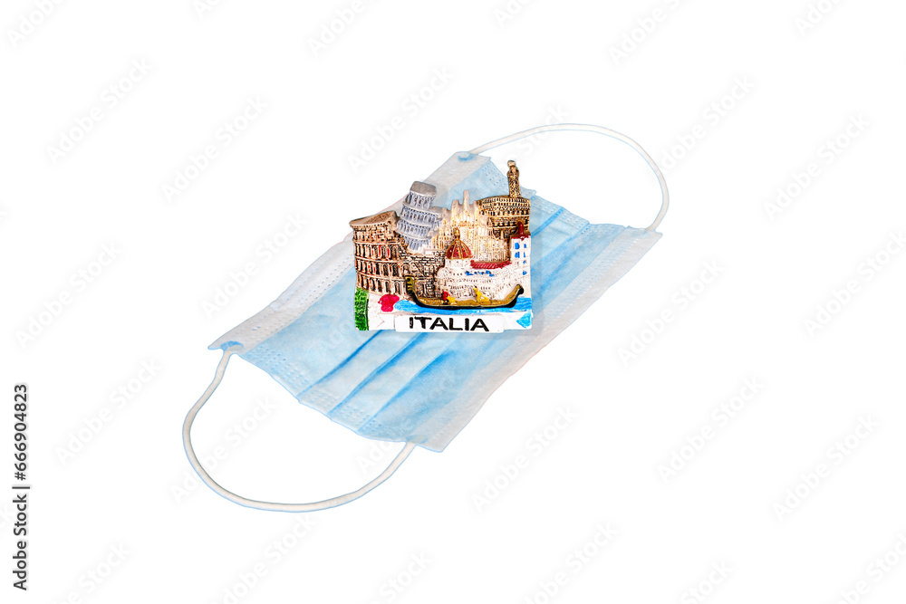 Obraz premium Medical mask and tourist magnet with the symbol of Italia, isolated on a white background. Signal tape as a symbol of quarantine from the coronavirus epidemic
