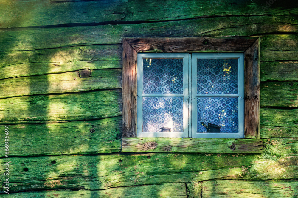 Window of an old wooden croft with green lichen on the wall - obrazy, fototapety, plakaty 