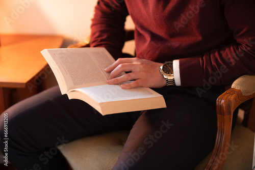 Well dressed man reading in home library, sitting in old chair