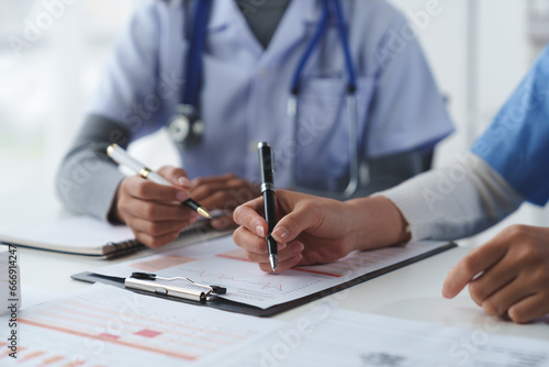 Confident female doctor, therapist sitting at table with medical stethoscope using laptop and mobile phone to write medical notes planning concept Study the treatment system Life insurance analysis.