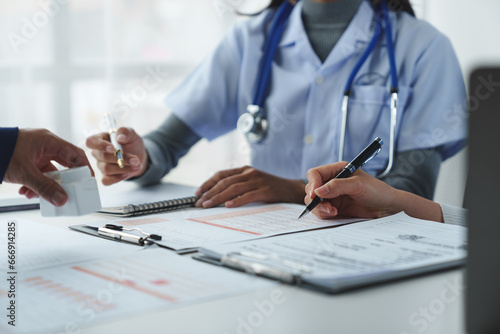 Confident female doctor, therapist sitting at table with medical stethoscope using laptop and mobile phone to write medical notes planning concept Study the treatment system Life insurance analysis. photo