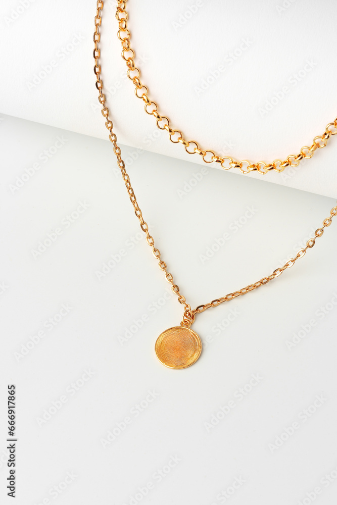 Golden chain with pendant on paper background close up Golden chain with pendant on paper background close up