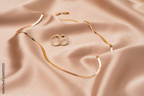 Golden chain necklace and earrings on silk background