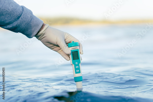 examination of water quality in natural reservoir. a device for measuring impurities in water in the male hand of a scientific specialist. photo